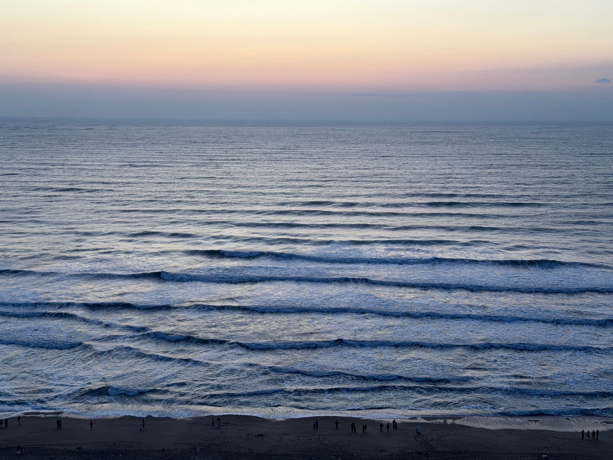 Waves rolling onto a sandy beach under a colorful sunset sky