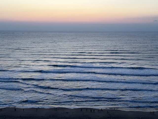 Waves rolling onto a sandy beach under a colorful sunset sky
