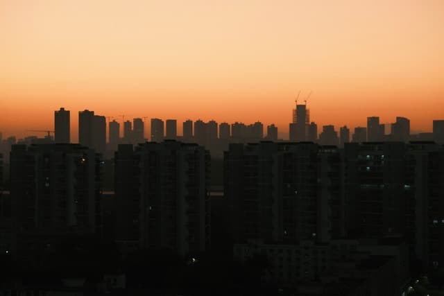 A city skyline silhouetted against a warm orange sunset