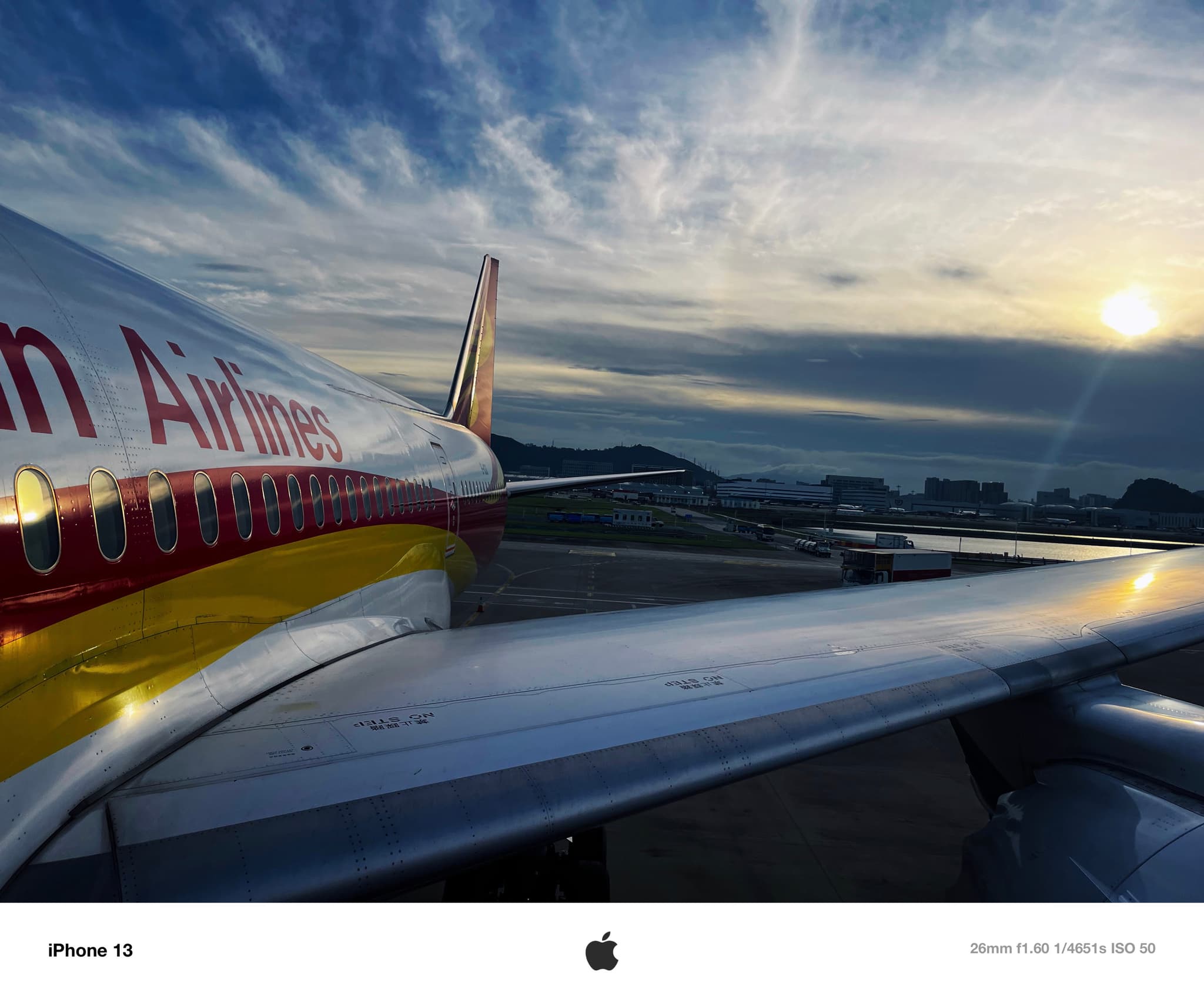An airplane wing and fuselage with vibrant airline branding, set against a dramatic sky during sunrise or sunset